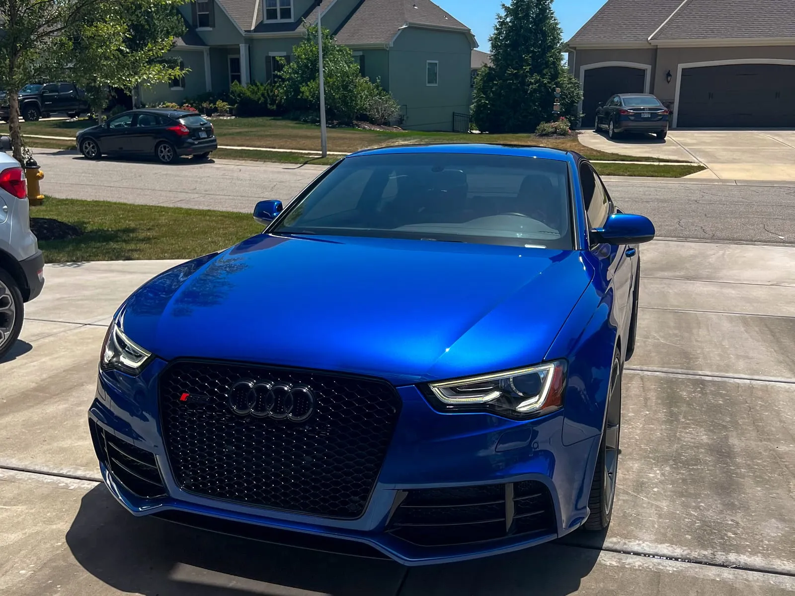 Blue Audi RS3 at a three-quarter front angle on a driveway, grille and headlights clean