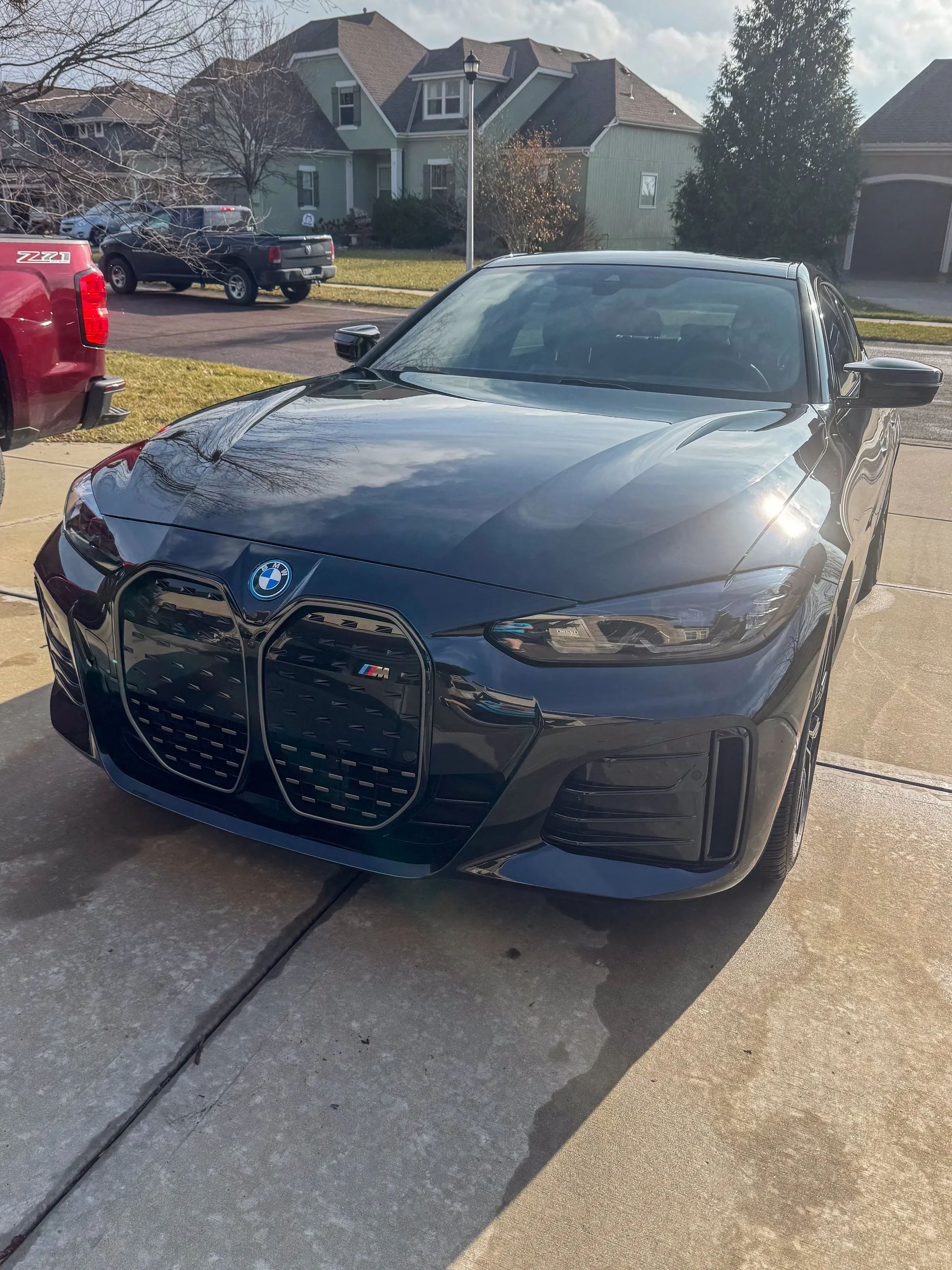 Black BMW i4 on a driveway, grille and headlights clean and the hood holding a sharp reflection
