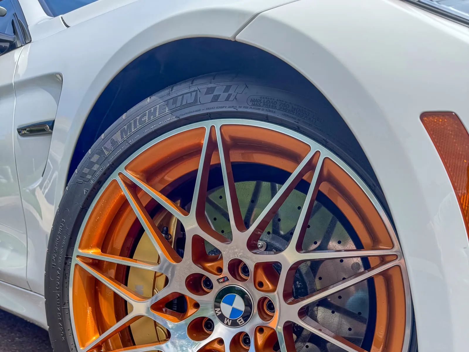 Close view of an orange BMW M double-spoke wheel and tire, cleaned to the barrel