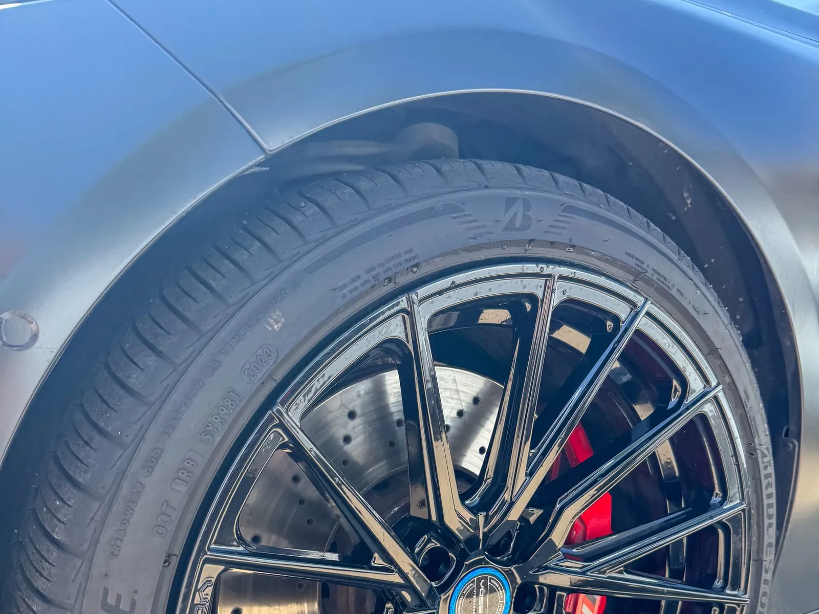 Close view of a black multi-spoke BMW wheel with a red brake caliper behind it, every spoke cleaned
