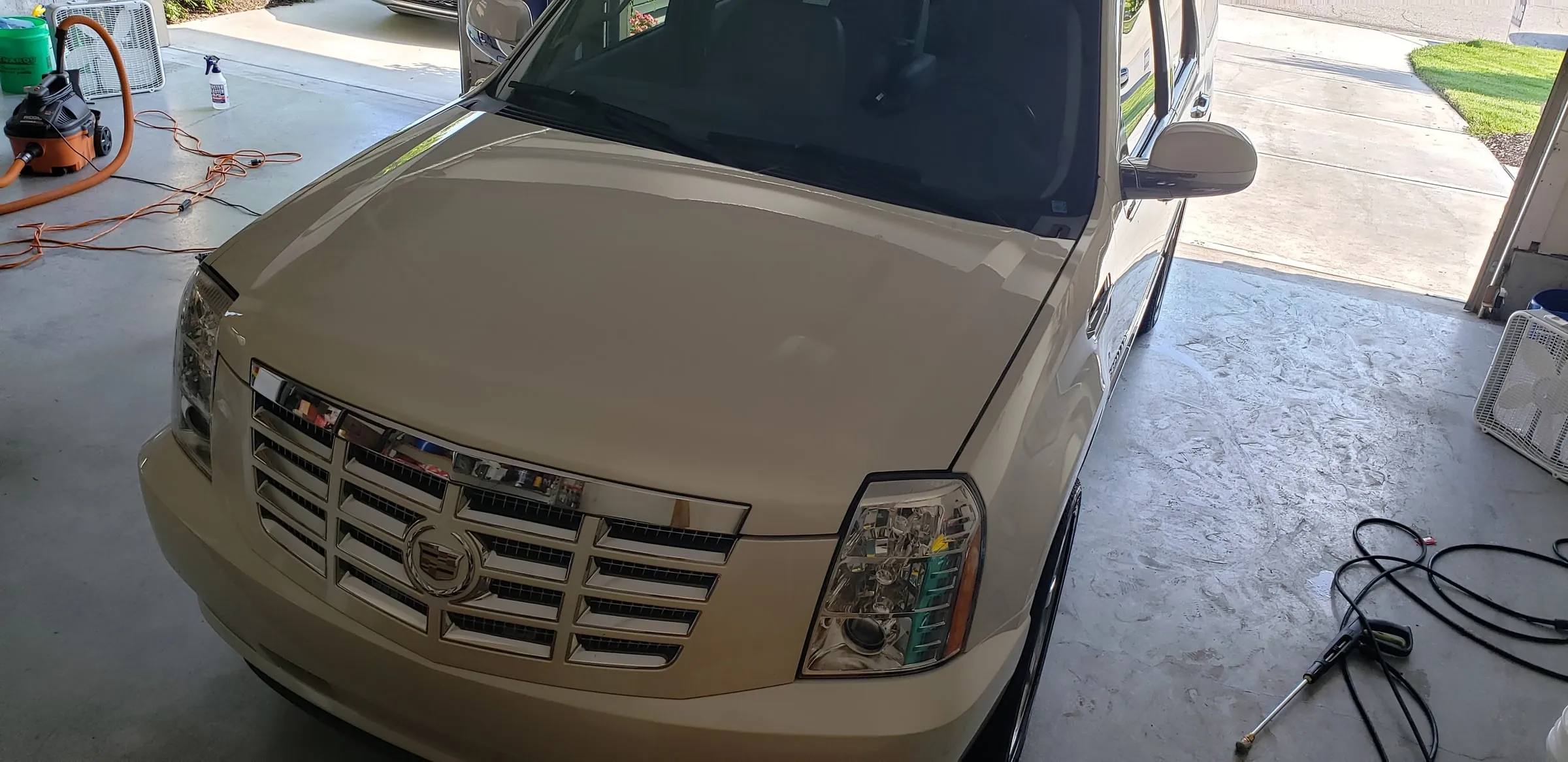 Front end of a cream Cadillac Escalade after washing, grille and headlights clear
