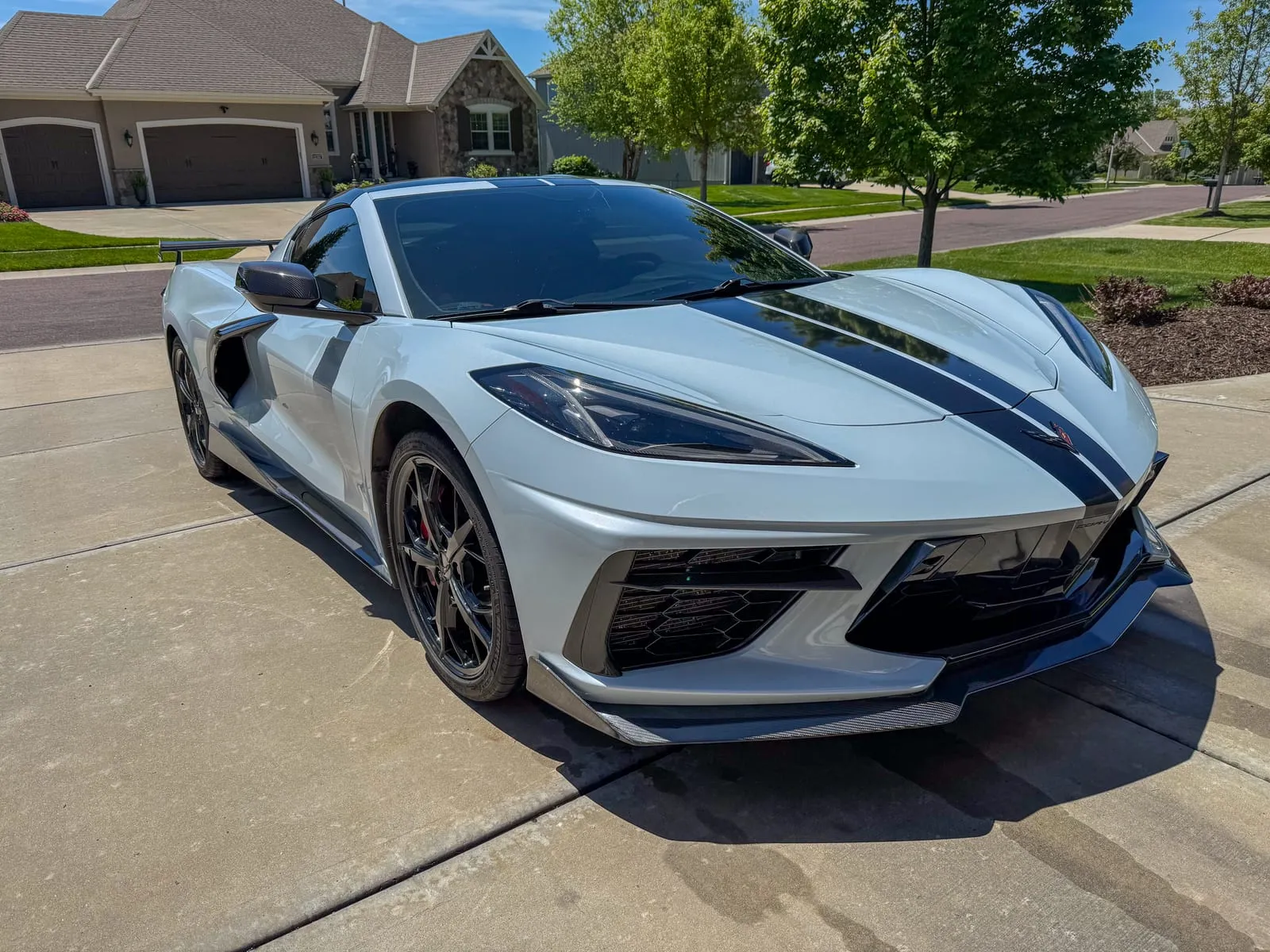 Silver Chevrolet Corvette C8 with black stripes on a driveway, front splitter and wheels clean