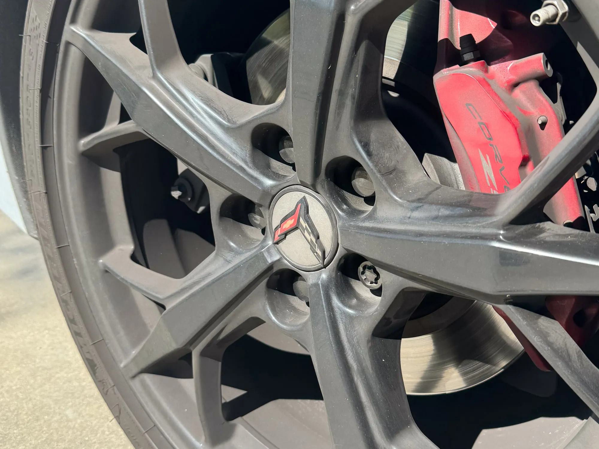 A C8 Corvette wheel dulled with brake dust and oxidation before decontamination