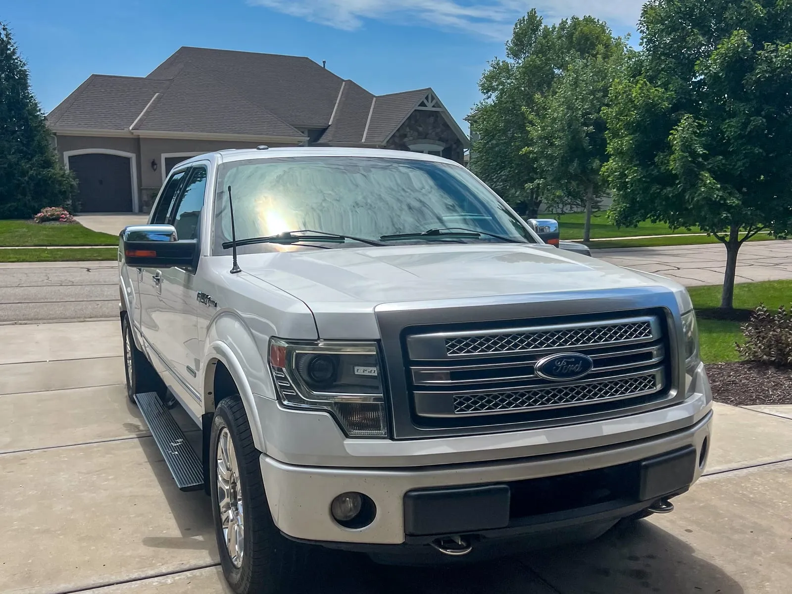 Silver Ford F-150 crew cab on a driveway in front of a brick house, wheels and grille cleaned