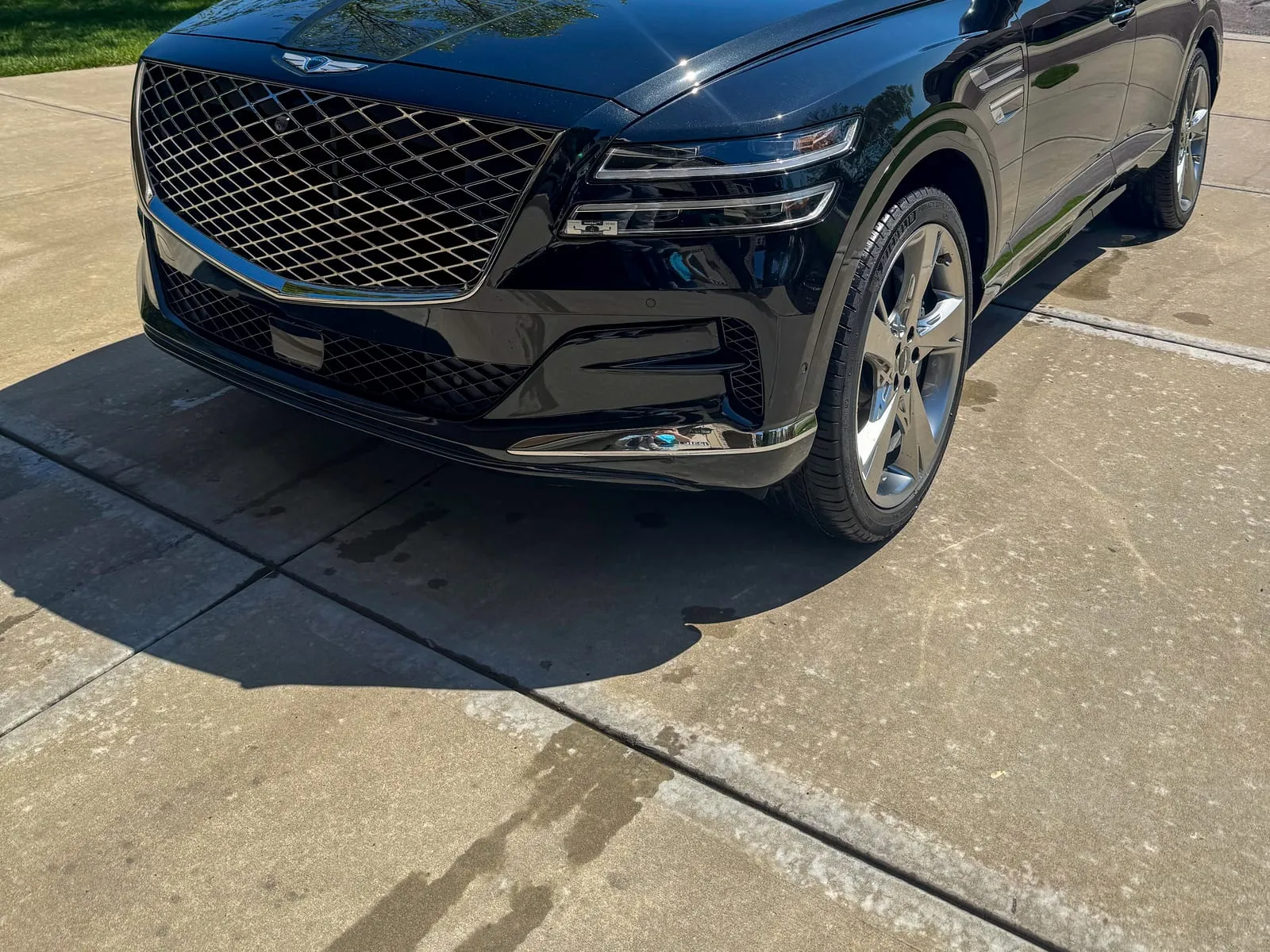 Black Genesis GV80 head-on in a driveway, the full mesh grille cleaned out