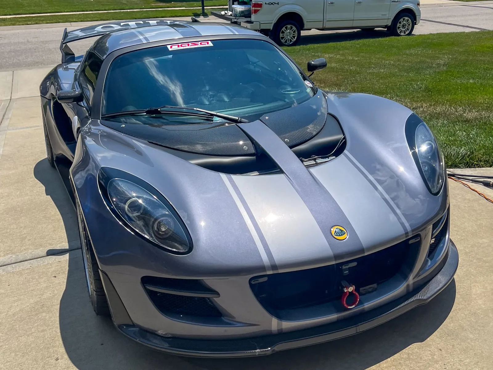 Silver and purple Lotus Exige on a driveway, front splitter and clamshell cleaned