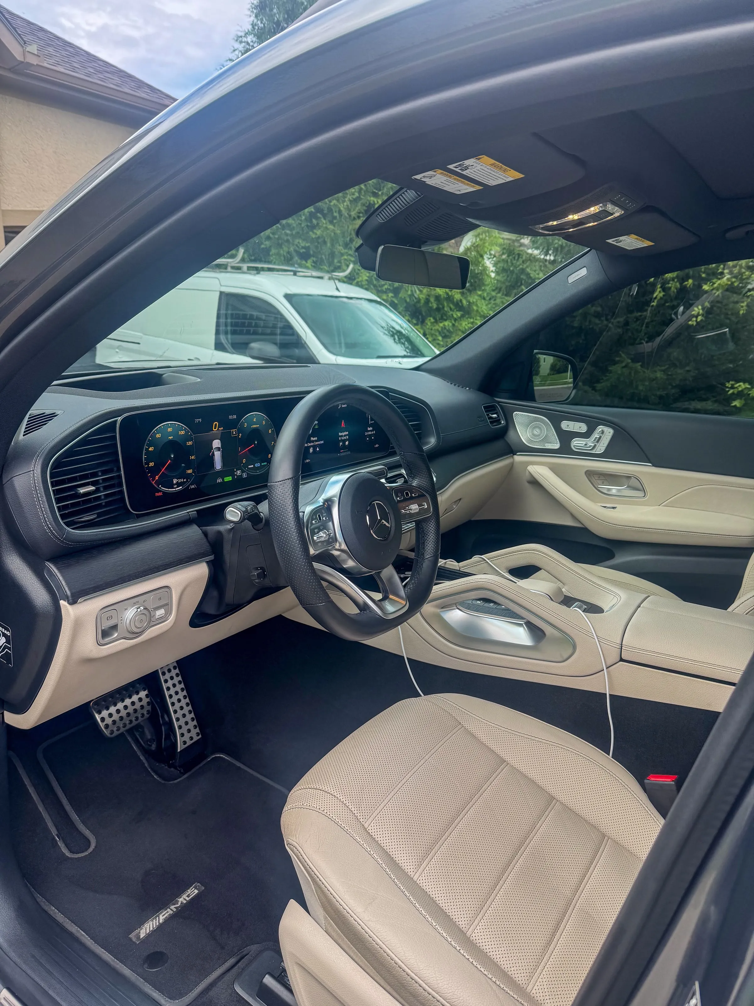 Driver side of a Mercedes-Benz GLS with cream leather seats, cleaned dash and instrument screens