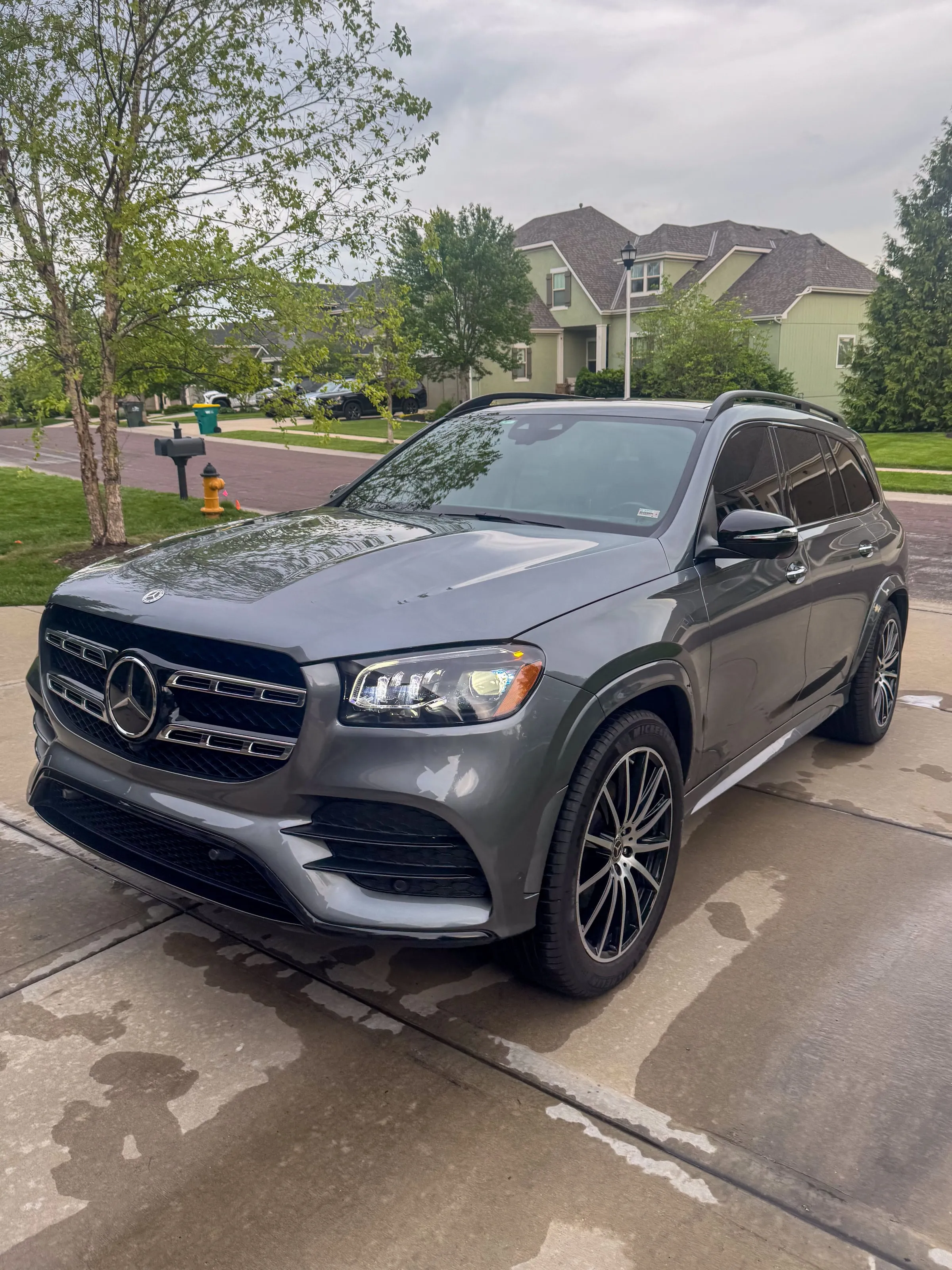 Grey Mercedes-Benz GLS at a three-quarter front angle on a wet driveway, wheels and grille cleaned