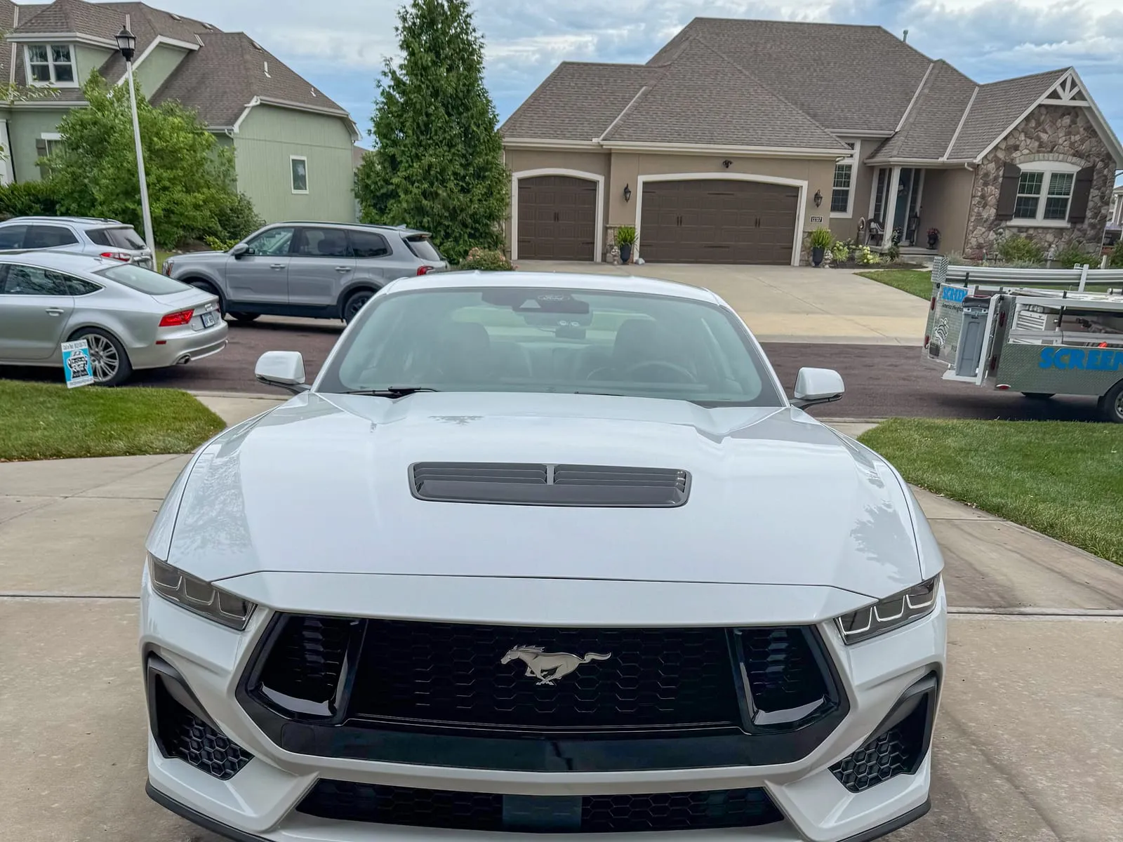 White Ford Mustang head-on in a driveway, hood vents and grille cleaned