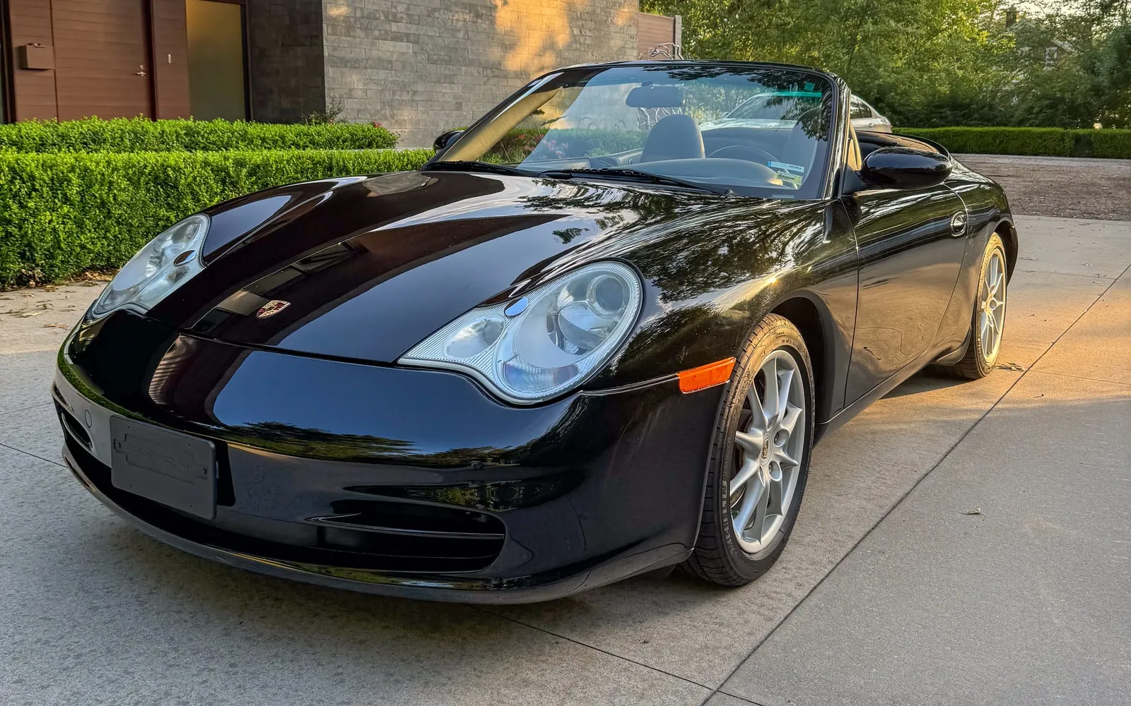 A black Porsche 911 Cabriolet with a mirror-polished finish, parked in a driveway