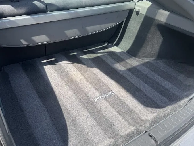 The cargo floor of a Toyota Prius after cleaning, carpet uniform and free of debris, parcel shelf above