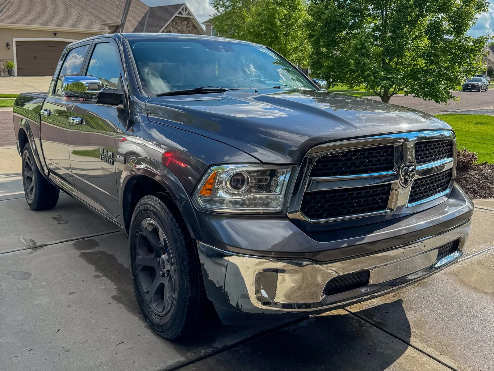 Black Ram 1500 crew cab on a driveway, chrome grille cleaned and tires dressed