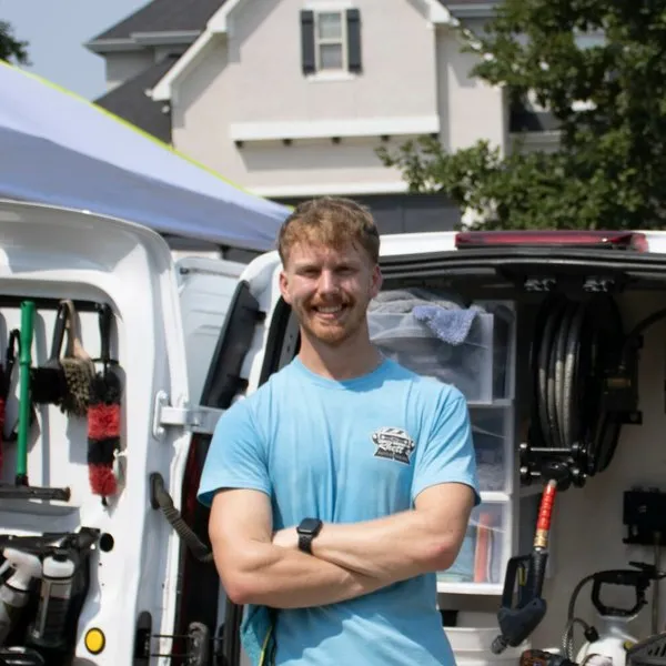 Rhett standing in front of his work van with its rear doors open