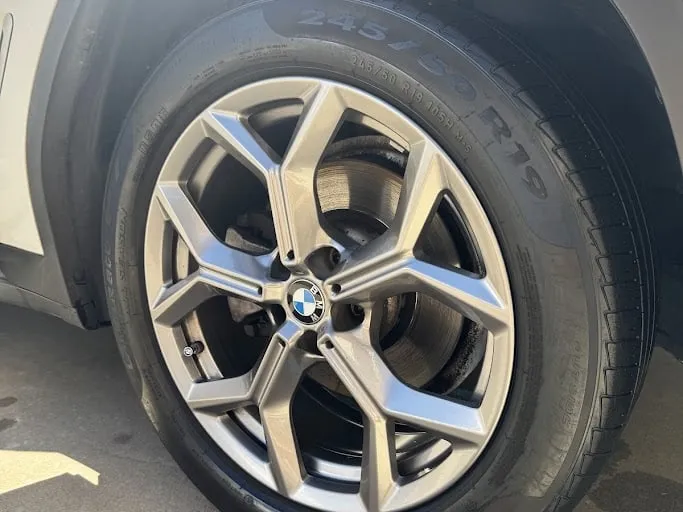 The same BMW alloy wheel cleaned and coated, back on the car, the machined face bright and the tire dressed